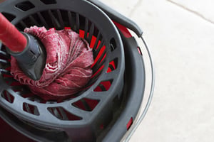 Red kitchen mop being used to clean a floor surface